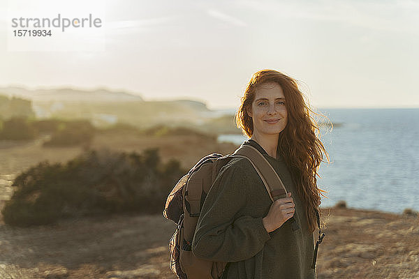 Porträt einer rothaarigen jungen Frau an der Küste bei Sonnenuntergang  Ibiza  Spanien