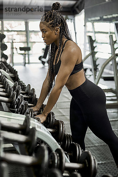 Sportlerin wählt Gewichte für das Training im Fitnessstudio