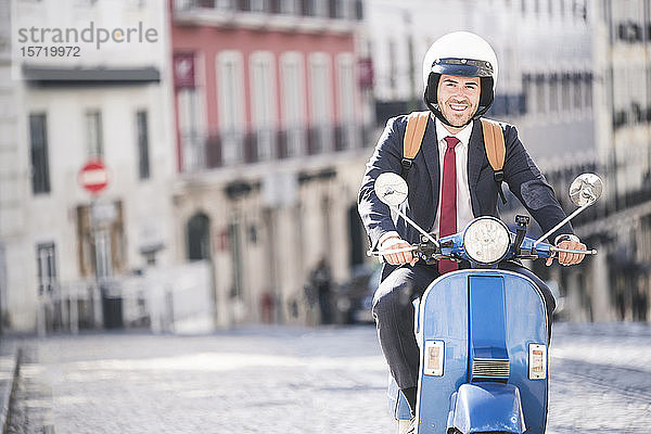 Porträt eines lächelnden jungen Geschäftsmannes auf einem Motorroller in der Stadt  Lissabon  Portugal
