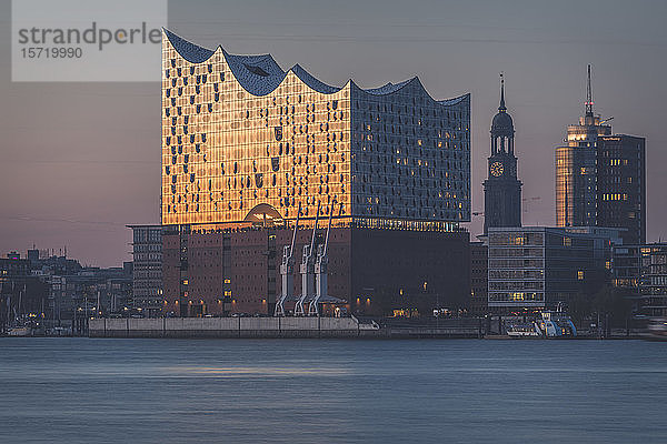 Deutschland  Hamburg  Elbphilharmonie in der Abenddämmerung mit der St. Michaels-Kirche im Hintergrund