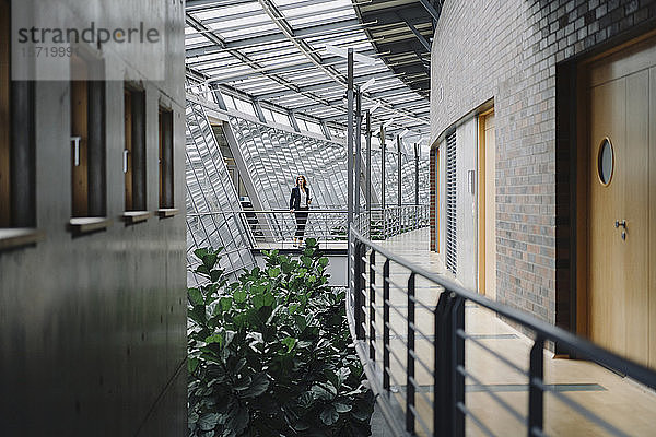 Geschäftsfrau  die auf einem Skywalk in einem modernen Bürogebäude steht
