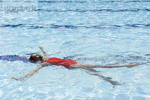 Junge Frau schwimmt im Schwimmbad auf dem Wasser
