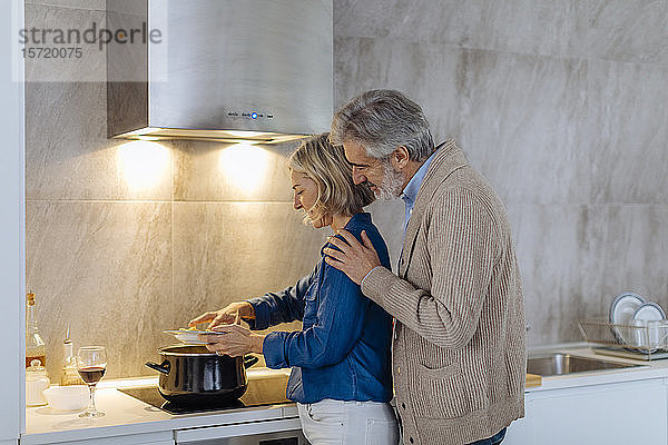 Reifere Paare bereiten das Abendessen zu Hause in der Küche zu