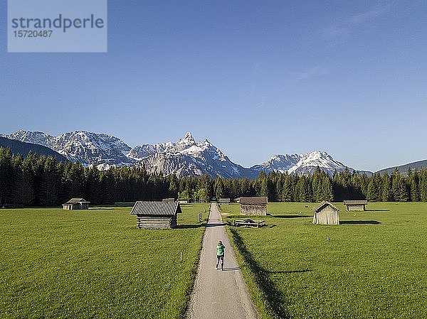 Wanderin auf einem Wanderweg  Heustadeln auf einer Wiese  Ehrwalder Sonnenspitz und Berge  bei Ehrwald  Mieminger Kette  Tirol  Österreich  Europa