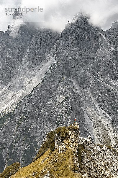 Bergsteiger  Frau auf einem Grat stehend und in ein Kar blickend  dramatische Wolken  in den hinteren Felswänden des Cimon di Croda Liscia  Auronzo di Cadore  Belluno  Italien  Europa