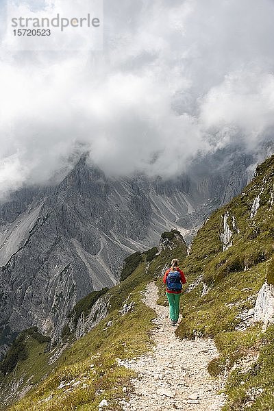 Junge Frau  Bergsteigerin auf einem Wanderweg  bewölkter Himmel  Cimon di Croda Liscia und Cadini-Gruppe  Sextner Dolomiten  Belluno  Italien  Europa