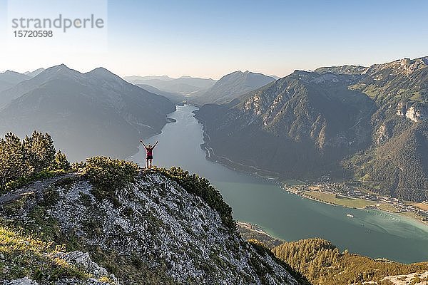 Junge Frau streckt die Arme in die Luft  Blick vom Bärenkopf zum Achensee  links Seebergspitze und Seekarspitze  rechts Rofangebirge  Tirol  Österreich  Europa