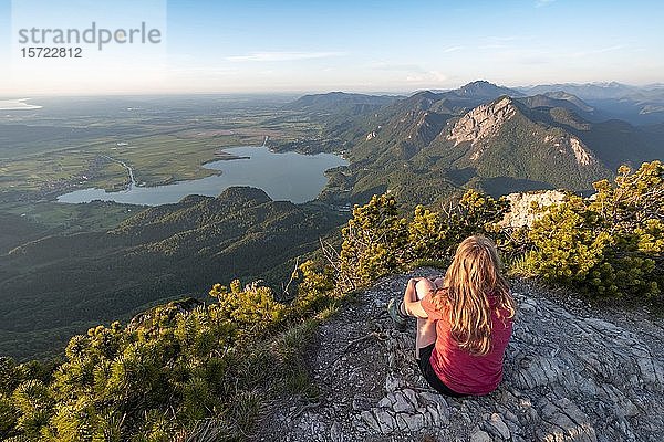 Junge Frau auf dem Gipfel sitzend  Blick vom Herzogstand zum Kochelsee  Jochberg und Alpenvorland  Alpen  Oberbayern  Bayern  Deutschland  Europa