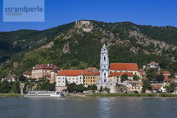 Ausflugsschiff auf der Donau vor der Barockkirche des Stiftes Dürnstein  im Hintergrund die Burgruine Dürnstein  Wachau  Niederösterreich  Österreich  Europa