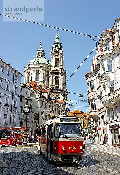 Rote Straßenbahn fährt durch eine Straße  St.-Nikolaus-Kirche  Kleinseite  Prag  Böhmen  Tschechische Republik  Europa