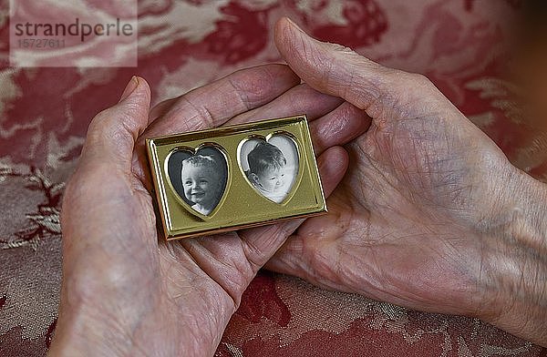 Symbolfoto  Mutterliebe  Hände einer alten Frau halten einen Bilderrahmen mit dem Porträt eines Kleinkindes  Tochter  Enkel  Erinnerung  Deutschland  Europa