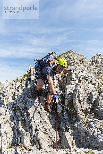 Bergsteiger  junger Mann klettert über Felsen  Bergsteiger auf einem gesicherten Klettersteig  Mittenwalder Klettersteig  Karwendelgebirge  Mittenwald  Deutschland  Europa