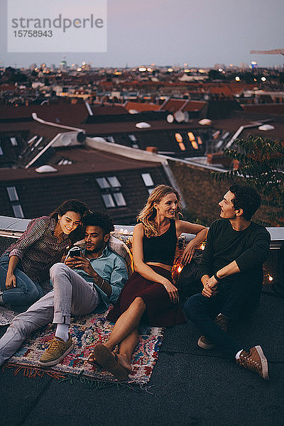 Schrägansicht von Freunden  die sich während einer Dachparty auf einer Terrasse in der Stadt entspannen