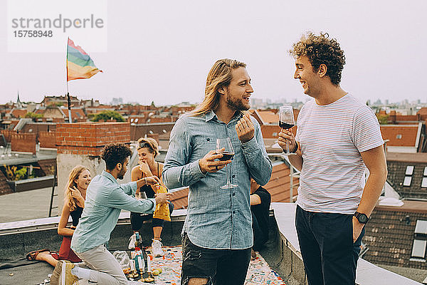 Freunde trinken Wein und unterhalten sich bei einer Dachparty auf der Terrasse