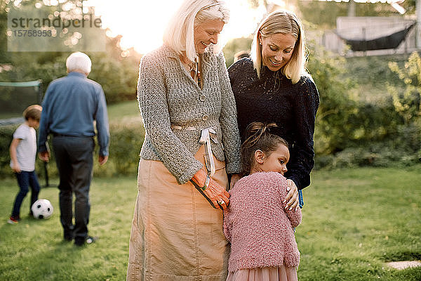 Mädchen umarmt sich mit Mutter und Großmutter  während sie im Hinterhof steht