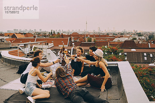 Fröhliche Freunde stoßen auf Bier an  während sie auf einer Terrasse in der Stadt entspannen