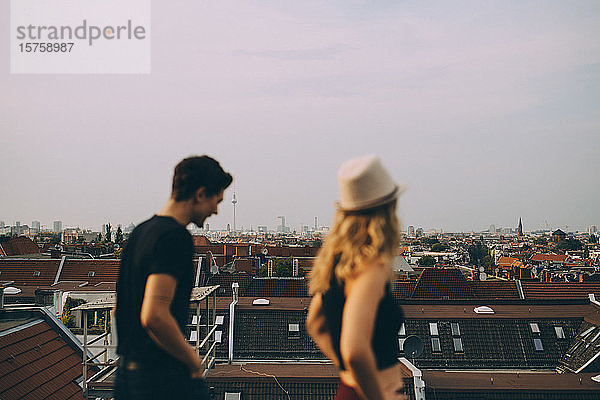 Freunde gehen auf Terrasse durch Stadtbild gegen Himmel