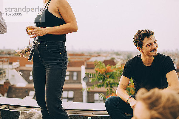 Frau mit Bier steht bei einem Freund und schaut bei einer Party auf der Terrasse weg