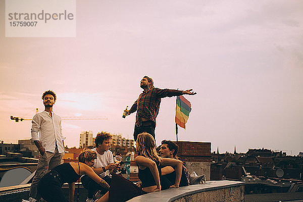 Mann genießt Bier und entspannt sich mit Freunden auf der Terrasse bei einer Dachparty
