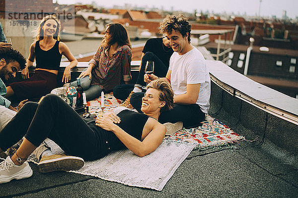 Fröhliche Freunde entspannen auf der Terrasse während einer Dachfeier