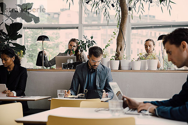 Männliche und weibliche Angestellte  die am Schreibtisch im Coworking Space arbeiten