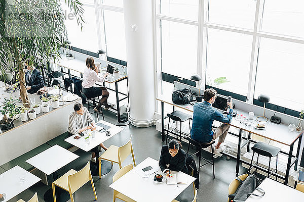 Schrägansicht von Geschäftskollegen  die am Schreibtisch im Coworking Space arbeiten