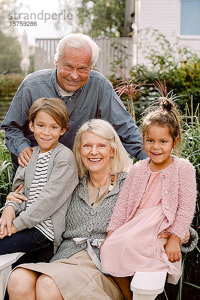 Porträt der Großeltern und Enkelkinder im Hinterhof sitzend