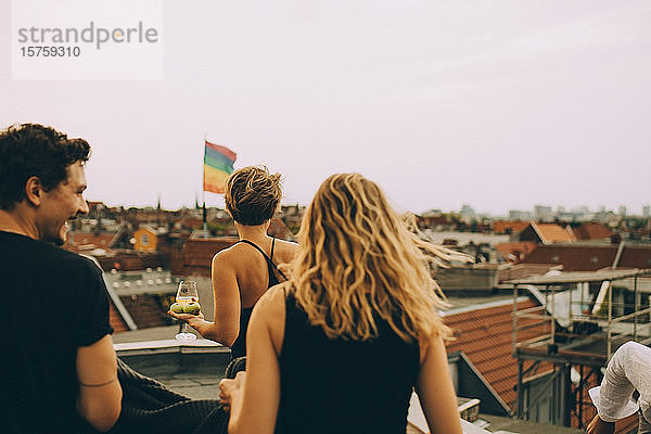 Rückansicht von Freunden  die während einer Dachparty gegen den Himmel auf der Terrasse spazieren