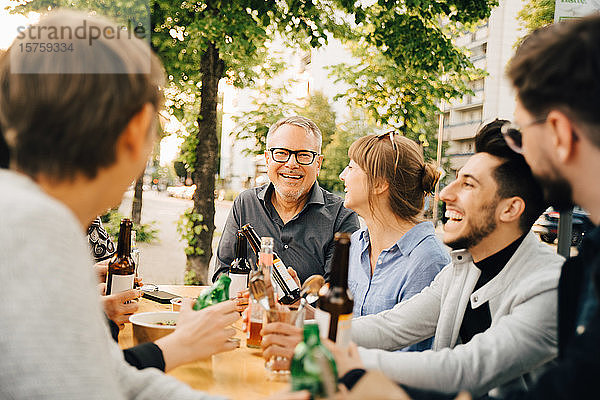 Porträt eines glücklichen reifen Mannes  der mit Freunden zusammensitzt und sich in geselliger Runde amüsiert