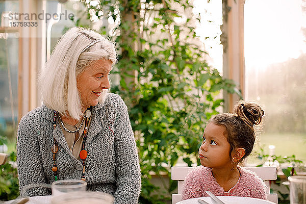 Lächelnde Großmutter sieht Enkelin beim Mittagessen an
