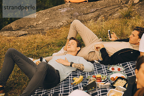 Hochwinkelaufnahme von männlichen Freunden auf einer Picknickdecke liegend