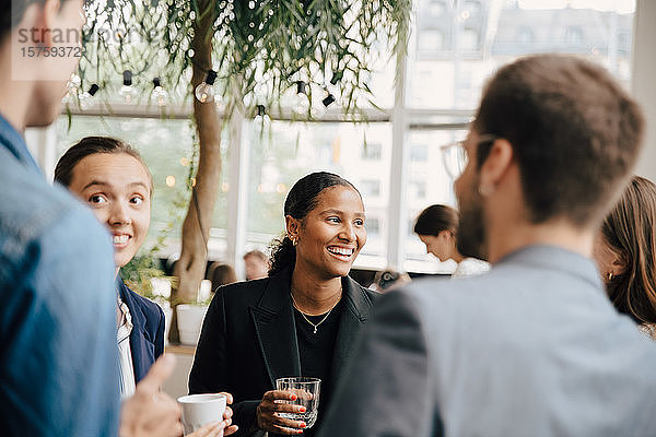 Lächelnde männliche und weibliche Kollegen diskutieren während der Kaffeepause