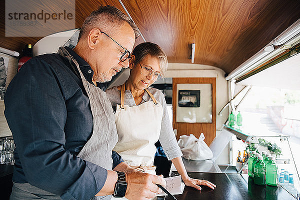 Reife Besitzer schauen auf Ordnung  während sie im Speisewagen stehen