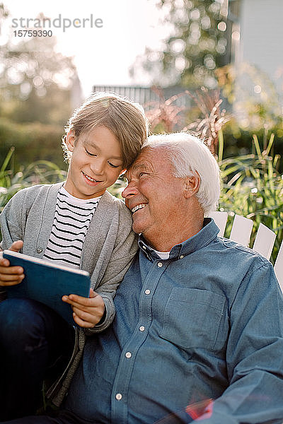 Lächelnder Großvater und Enkel benutzen digitales Tablett im Hinterhof