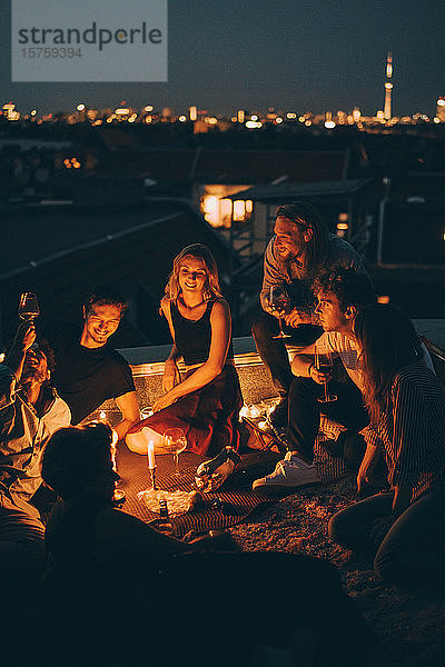 Hochwinkelansicht von Freunden  die auf der Dachparty auf der beleuchteten Terrasse bei Kerzenschein feiern