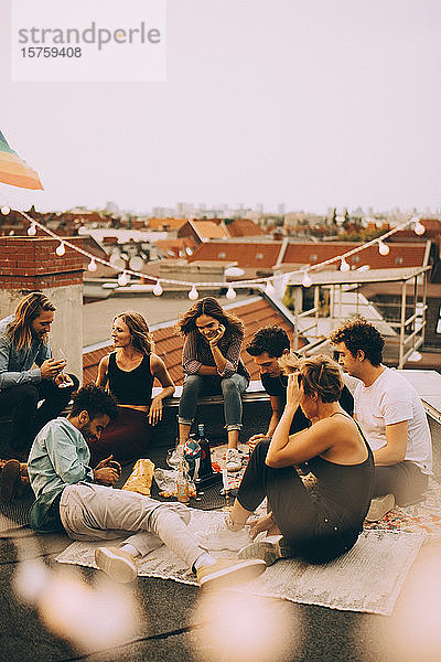 Männliche und weibliche Freunde genießen Dachparty auf der Terrasse in der Stadt