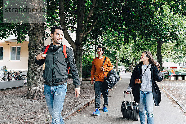 Junge Freunde gehen in der Stadt mit Gepäck auf der Straße