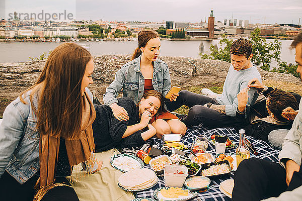 Männliche und weibliche Freunde genießen Essen auf einer Picknickdecke