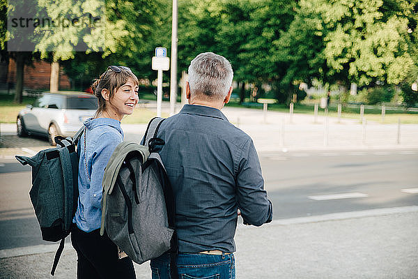 Fröhliche Frau spricht mit reifem Mann beim Spaziergang in der Stadt
