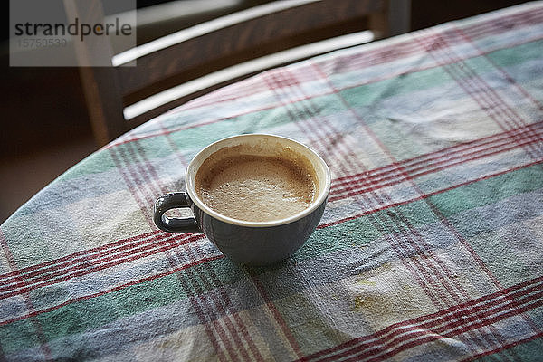 Tasse Kaffee auf mit kariertem Tuch bedecktem Tisch