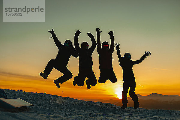 Freunde springen vor Freude gegen den Sonnenuntergang  Karpaten  Ukraine