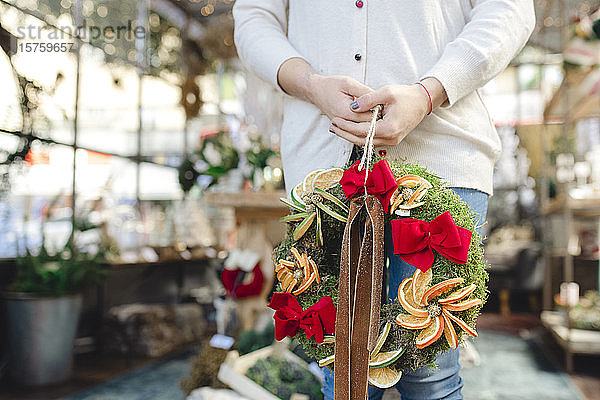 Frau hält Weihnachtskranz im Geschäft