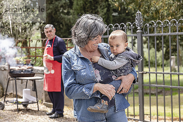 Grossmutter trägt einen kleinen Jungen beim BBQ-Treffen der Familie  Florenz  Italien