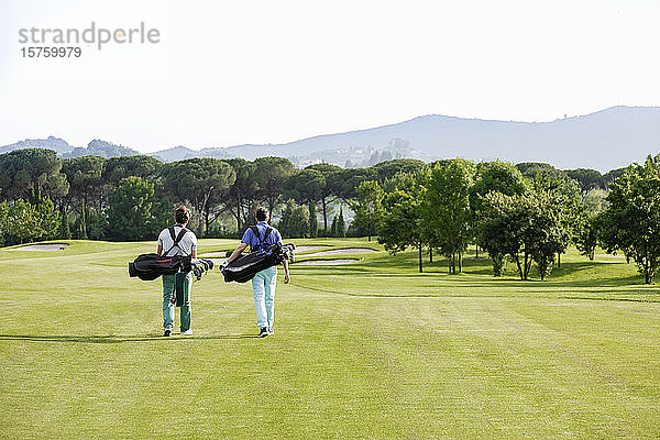 Freunde tragen Golftasche beim Gehen auf dem Golfplatz
