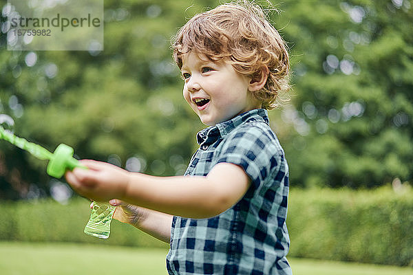 Kleinkind spielt mit Seifenblasen im Park