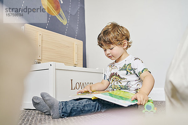 Kleinkind liest Buch im Zimmer