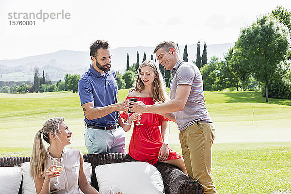 Freunde genießen Wein und unterhalten sich auf dem Sofa auf dem Golfplatz