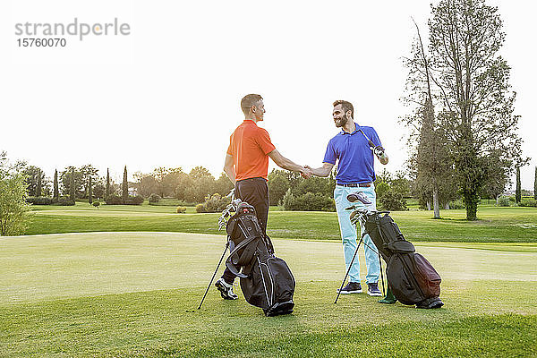 Freunde schütteln Hände auf dem Golfplatz