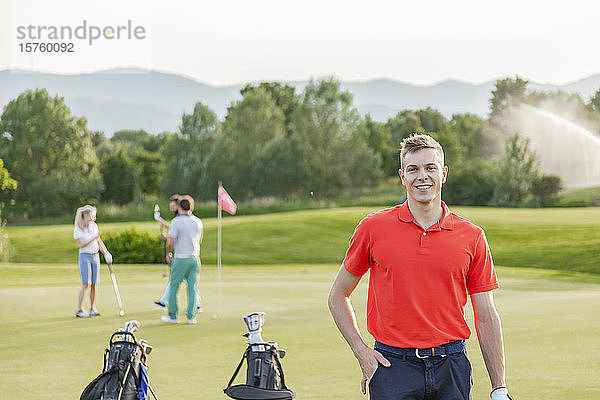 Mann mit Freunden beim Golfspielen auf dem Golfplatz im Hintergrund