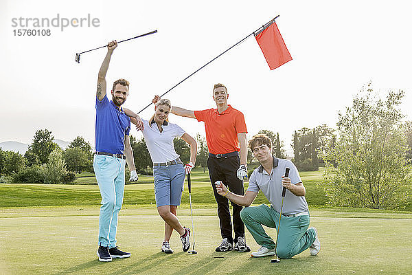 Freunde schwenken Flaggenstock auf dem Golfplatz